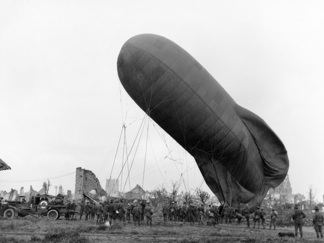 Een kabelballon klaar om op te stijgen tussen de ruïnes rond Ieper, omringd door soldaten.