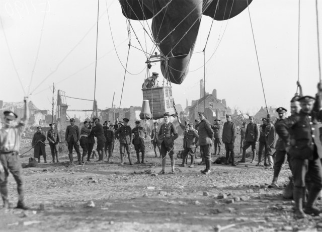 Een officier in de mand van een kabelballon in Ieper, met kapotgeschoten gebouwen op de achtergrond.